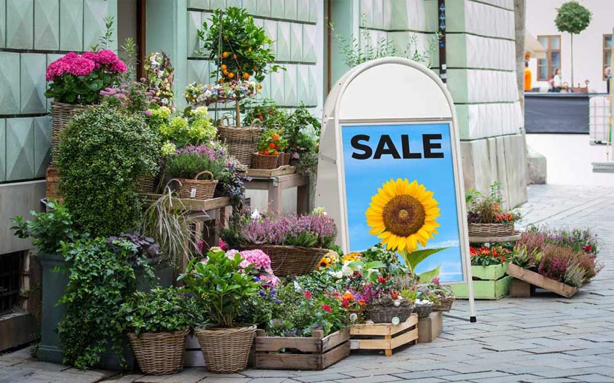 An advertising poster for a flower shop in a metallic advertising stand with the poster in a plastic pouch
